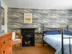 a bedroom with a bed and a fire place at Swallow Cottage in Llandwrog