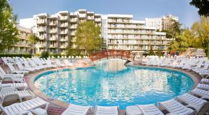 a large swimming pool with white chairs and a building at Hotel Laguna Mare in Albena