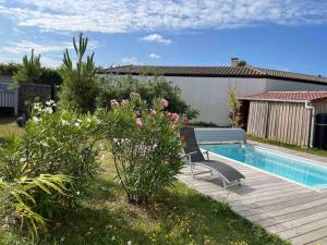 einen Pool mit zwei Stühlen neben einem Hof in der Unterkunft Maison Oléron avec piscine in Le Trait dʼUnion