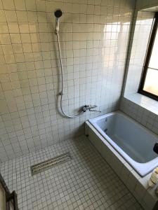 Gentou - Vacation STAY 28719v في آسو: حمام ذو بلاط أبيض مع حوض استحمام ونافذة
