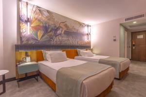 アンタルヤにあるベストウエスタン プラス カーン ホテルのベッド2台が備わる客室で、壁には絵画が飾られています。