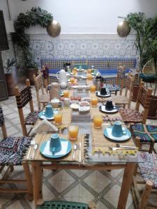 un lungo tavolo in legno con piatti e bicchieri di succo d'arancia di Riad Papadou a Marrakech