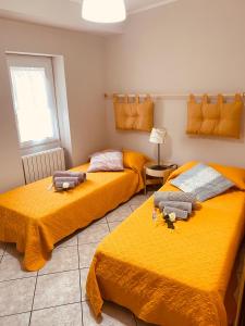two beds in a room with yellow sheets at Matteo's House in Penne