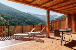 eine Terrasse mit einem Tisch, Stühlen und Bergen in der Unterkunft Hotel Miravalle in Valdidentro