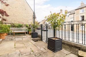 a black fence with two potted trees and a bench at 3 bedroom converted chapel in historic Oundle in Oundle
