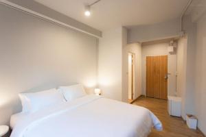 a bedroom with a white bed and a wooden floor at Hotel PAPA Bangkok Siriraj in Bangkok