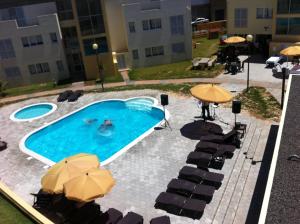 una piscina con sombrillas, mesas y sillas en Paraiso Dourado en Porto Santo