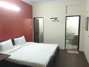 a bedroom with a large white bed and a bathroom at Hotel Sharma Residency Chennai Egmore in Chennai