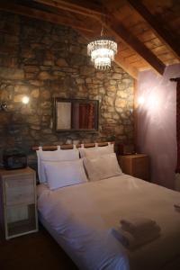 a bedroom with a large bed with a stone wall at Guesthouse Kontogianni - Materka in Nymfaio