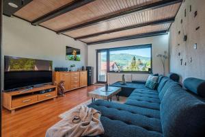 - un salon avec un canapé bleu et une grande fenêtre dans l'établissement Apartmán Jizerské hory, à Hejnice