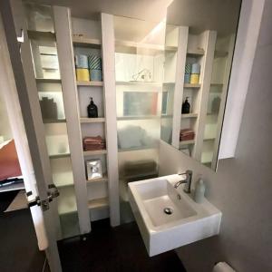 uma casa de banho com um lavatório branco e um espelho. em Boutique City Apartment with Iconic Mountain Views em Camberra