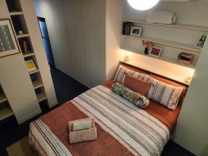 um pequeno quarto com uma cama com almofadas em Boutique City Apartment with Iconic Mountain Views em Camberra