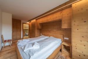 - un grand lit dans une chambre dotée de murs en bois dans l'établissement Chesa Diala - Zuoz, à Zuoz
