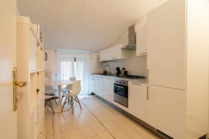 ヴェローナにあるAppartamento Scaligero Borgo Trentoのキッチン(白いキャビネット、テーブル、椅子付)