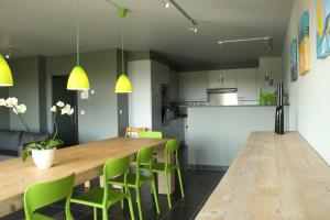 ニーウポールトにある"Zonnesteiger" ruim appartement met parkingのキッチン(長い木製テーブル、緑の椅子付)