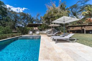 an outdoor swimming pool with two lounge chairs and an umbrella at Horizon Hill Villa in Pirae