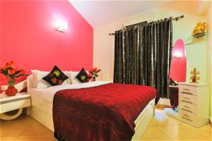 - une chambre avec des murs roses et un lit avec une couverture rouge dans l'établissement La Goa Villa - 4BHK, Baga, à Baga