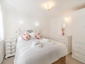 a white bedroom with a white bed with pink pillows at Honeysuckle Cottage- Uk45594 in Verwick