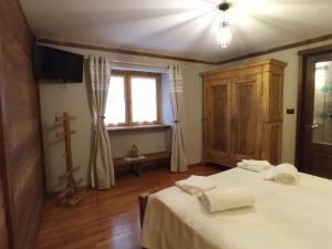 1 dormitorio con 2 camas, ventana y cruz en La Randoulino, en Pomaretto