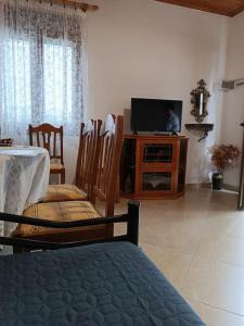 een woonkamer met een tv en een tafel en stoelen bij Mary's Traditional home in Aigáni