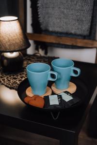 two blue cups and cookies on a tray on a table at Sniegi Apartments with sauna in Madona