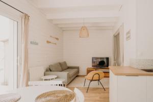 ein weißes Wohnzimmer mit einem Sofa und einem Tisch in der Unterkunft Sous le Saule, entre lac et océan in Naujac-sur-Mer