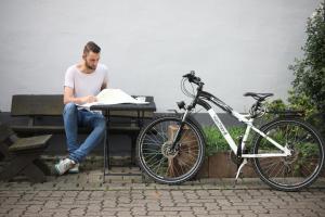 Ein Mann, der an einem Tisch neben einem Fahrrad sitzt. in der Unterkunft Hotel Duwakschopp in Herxheim
