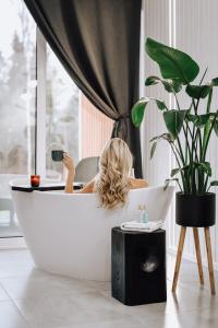 a woman sitting in a bath tub in a room at Sniegi design cabins with sauna in Madona