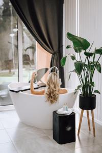 a woman sitting in a bath tub with a laptop at Sniegi design cabin with sauna in Madona +29 photos