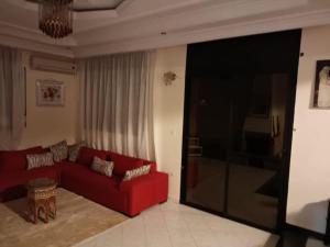 salon z czerwoną kanapą i telewizorem w obiekcie Villa à la décoration marocaine w mieście Rabat