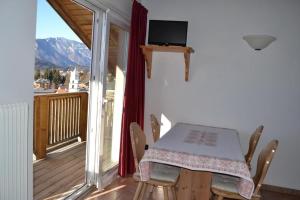 a table and chairs in a room with a balcony at Giongo Residence - Appartamenti in Lavarone