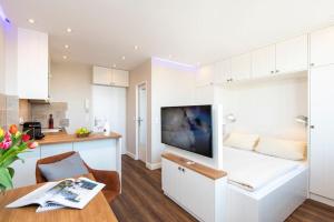 a kitchen and living room with a tv and a table at Exklusive Wohnung im Herzen Westerlands in Westerland