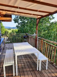 a wooden deck with a bench and a pergola at CHALET RONDIN JURA in Aromas