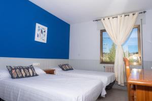two beds in a room with a blue wall and a window at Hostal Venta de Valcorba in Soria