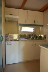 a kitchen with white cabinets and a sink and a stove at Bungalows, Camping Vega de Francia in Sotoserrano