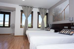 two beds in a room with windows at Hostal Venta de Valcorba in Soria