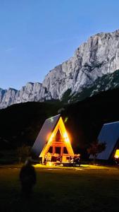 a small house with lights in front of a mountain at Etno apartmani Komarnica in Šavnik