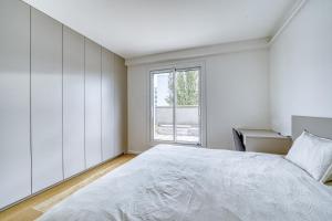 a white bedroom with a large bed and a window at Superbe 2 pièces 52 m2 refait à neuf Boulogne Nord - Superb brand new 1 bedroom appartement North of Boulogne in Boulogne-Billancourt