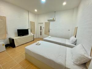 a bedroom with two beds and a flat screen tv at Whitehouse cafe&Guesthouse in Ban Sa La