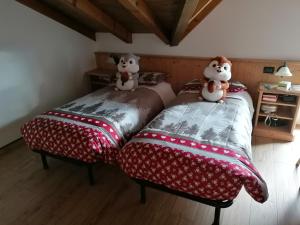 2 letti con orsacchiotti seduti sopra in una stanza di Giongo Residence - Appartamenti a Lavarone