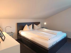 - une chambre dotée d'un grand lit avec des draps et des oreillers blancs dans l'établissement Alpenrose, à Obermaiselstein