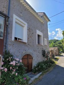 une maison en pierre avec une porte et un chien dans une fenêtre dans l'établissement Maison de Village en pierres, à Le Poët