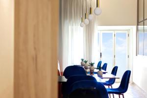 una sala da pranzo con sedie blu, tavolo e finestra di U259 B&b a Napoli