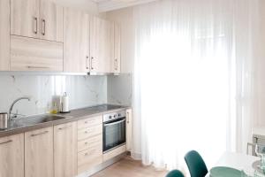 a kitchen with white cabinets and a sink and a window at Lake View Terrace Apartment in Kastoria