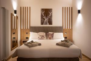 Un dormitorio con una gran cama blanca con un ciervo. en Hotel Villa Melì, en Predazzo