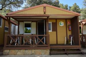 Bungalows, Camping Vega de Francia في Sotoserrano: منزل صغير مع شرفة وسطح