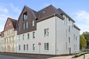a white building with a brown roof at SHINY HOMES - Kitchen - Free Parking - Netflix in Bielefeld