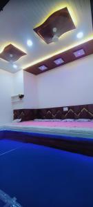 a bed in a room with a blue light at PRABHU PALACE in Ujjain