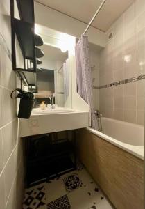 ein Badezimmer mit einem Waschbecken, einer Badewanne und einem Spiegel in der Unterkunft Chaleureux studio à 150m du Point Show in Vars