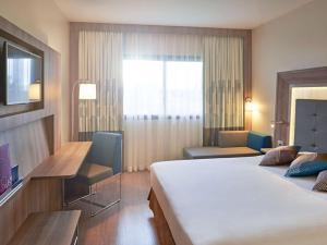 a hotel room with a large bed and a desk at Novotel Campo Grande in Campo Grande